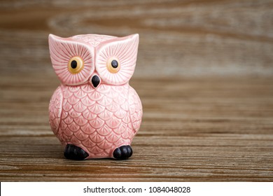 Pink owl figurine on wooden background