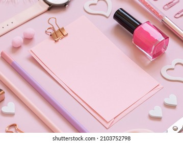 Pink paper card with clip, school girlish accessories and hearts on pastel pink close up, blank card mockup. Girly workplace. Back to school and valentines day concepts