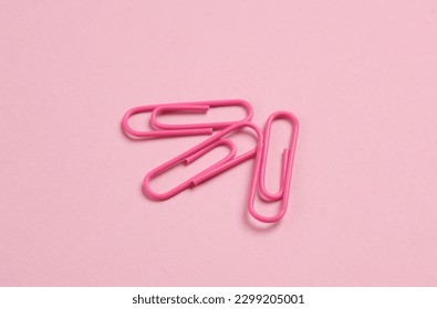 Pink paper clips on pink background
