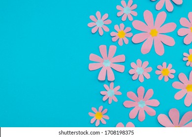 Pink paper flowers on a bright blue background. Room for copy.