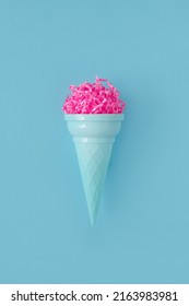 Pink paper ice cream scoop with ice cream plastic cone on bright blue background. Minimal summer concept. Micro plastic in food. Recycling.
