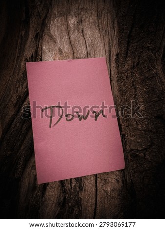 pink paper note with word Down on wood