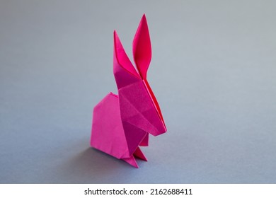 Pink paper rabbit origami isolated on a blank grey background.