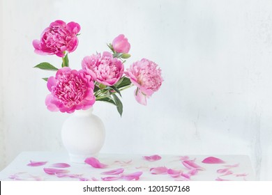 pink peonies in vase on vintage white wooden shelf