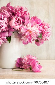 Pink peonies in vase on wood background