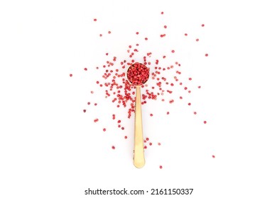 Pink peppercorns shot from overhead on white background, shown overflowing from spoon, pot onto table, space for text,
