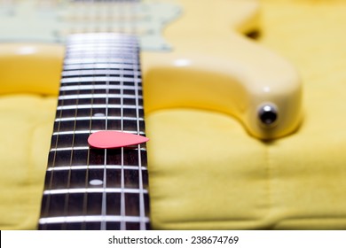 pink pick on yellow electric guitar fingerboard, shallow dept of filed