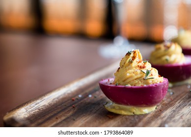 Pink Pickled Deviled Eggs On A Wooden Plate