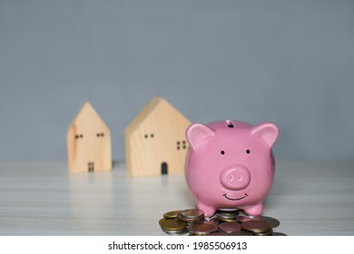 Pink Pig Piggy Bank On A Pile The Coin Is Placed On A Wooden Counter. Concept For Finance, Banking, Savings, Home, House, Sale, Tax. Closeup, Copy Space On Top For Design, Blurred Background.