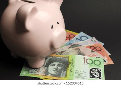 Pink Piggy Bank with Australian money against a black background, for savings concept.