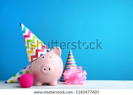 Pink piggy bank with birthday cap on blue background