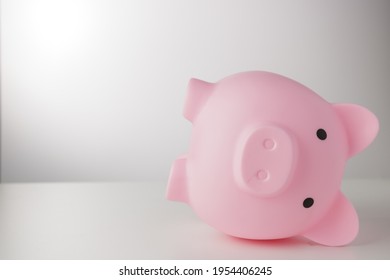 Pink Piggy Bank Falling Down On White Table Isolated On White Background. Represents The Troubled Or Failed Finance, Or Failed Deposit Money No Wealth. Money Deposit And Finance Concept.2