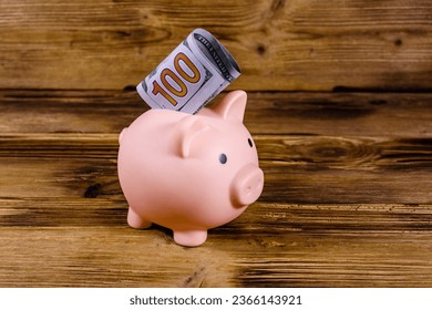Pink piggy bank with one hundred dollar bill - Shutterstock ID 2366143921