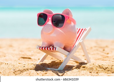 Pink Piggy Bank With Sunglasses On The Small Deck Chair At Beach