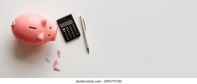 Pink Piggy Bank A White Color With A Notepad And Calculator. The Concept Of Saving Money, Finance, And Budget Planning.