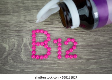 Pink pills forming shape to B12 alphabet on wood background