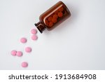 pink pills are poured from a jar on a bright white background.