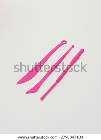 Pink plastic modeling tools for clay and playdough on white background