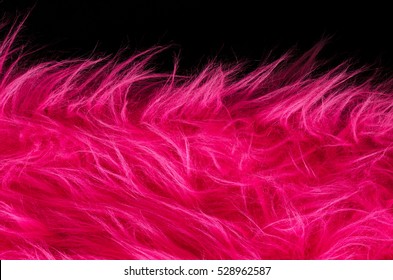 Pink plush fabric on black background horizontal. Very soft polyester textile made of synthetic fibers with long hairs. Macro close up material photography, front view.