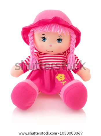 Pink plushie doll isolated on white background with shadow reflection. Cute pinky rag baby doll sitting on white underlay. Nice contemporary rag baby with pink hair. Modern joyfully rag baby with cap.