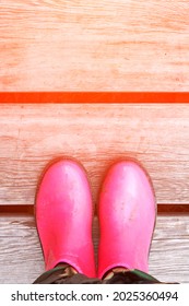 Pink Puddle. Rain Bright Boots. Dirty Safety Shoes. Summer Weather. Walking At Mountains. Person Feet. Rainy. Wood Background