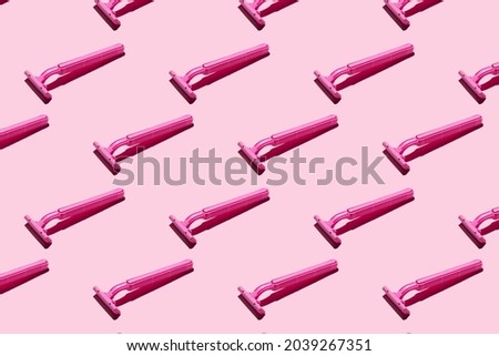 Pink razors on a pink background, pattern. Hard shadows. The concept of hair removal, body care.