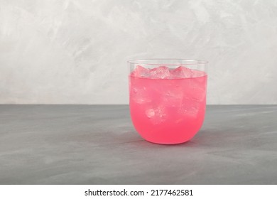 Pink Refreshing Iced Drink. Summer Fruit Cocktail In Clear Glass On Grey Background. Pink Lemonade With Ice Cubes.