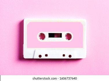 Pink retro cassette tape on pink background, top view.