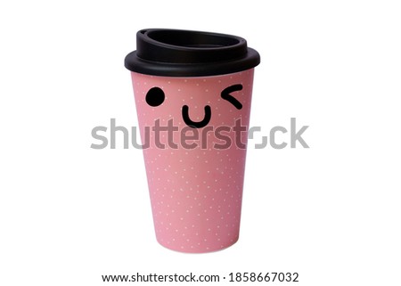 Pink reusable cup of coffee with white dots and cute kawaii face which is winking. Taked on separated background