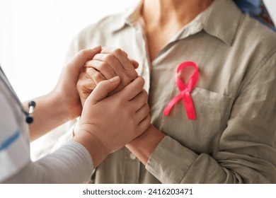 Pink ribbon for breast cancer awareness. Female patient listening to doctor in medical office. Support people living with tumor illness. - Powered by Shutterstock