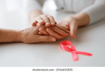 Pink ribbon for breast cancer awareness. Female patient listening to doctor in medical office. Support people living with tumor illness. - Powered by Shutterstock