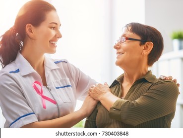 Pink ribbon for breast cancer awareness. Female patient listening to doctor in medical office. Raising knowledge on people living with tumor illness.
