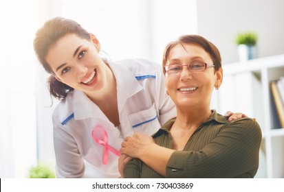 Pink ribbon for breast cancer awareness. Female patient listening to doctor in medical office. Raising knowledge on people living with tumor illness. - Powered by Shutterstock