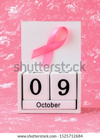 Pink ribbon of breast cancer awareness on a white wooden perpetual calendar with date 09 october. International breast cancer awareness month. Healthcare.