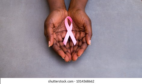 Pink Ribbon Close Up In Dark Brown Skin African Hand For Breast Cancer Concept On Dark Background 