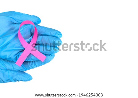 Pink ribbon in the hand of a doctor or nurse isolated on white, breast cancer struggle symbol
