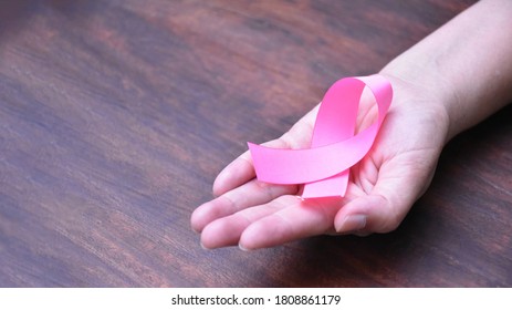 The pink ribbon in hand, a symbol of the global women's breast cancer campaign. - Shutterstock ID 1808861179
