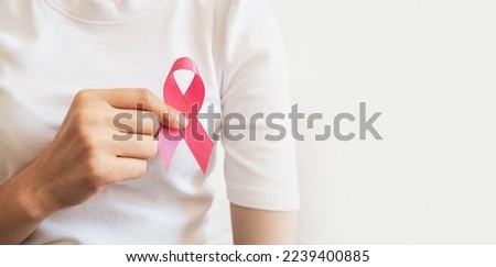 Pink ribbon on the chest of a woman in a white t-shirt. Symbol of breast cancer awareness campaign. Healthcare concept 