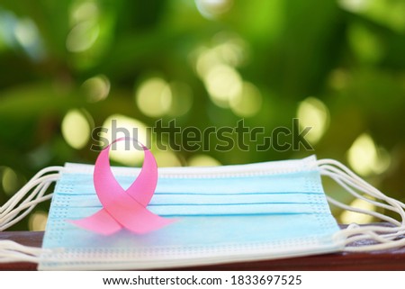 pink ribbon on protective face mask soft focus background blurred nature.concept breast cancer awareness with new normal
