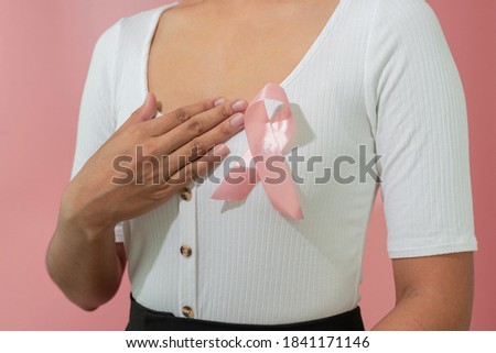 Pink ribbon on woman chest to support breast cancer. Healthcare and breast cancer awareness concept.