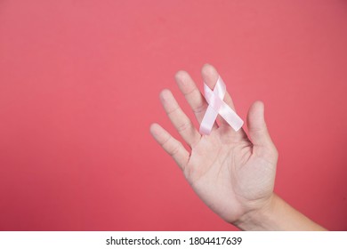 Pink ribbon on a woman hands on pink background. Breast cancer, healthcare and medicine concept, symbolic tape - Shutterstock ID 1804417639