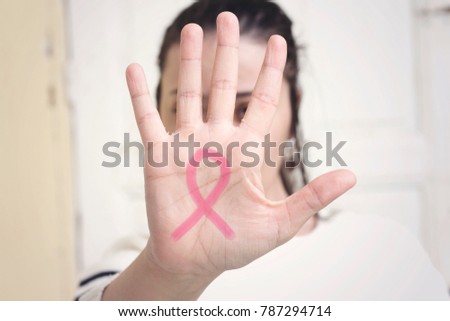 a pink ribbon painted in the palm of a young caucasian woman 