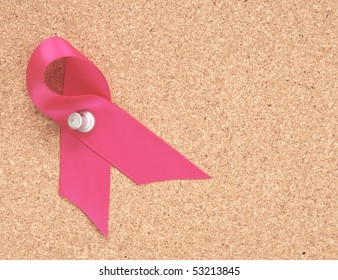 Pink Ribbon Pinned To A Corkboard To Remember Breast Cancer Awareness