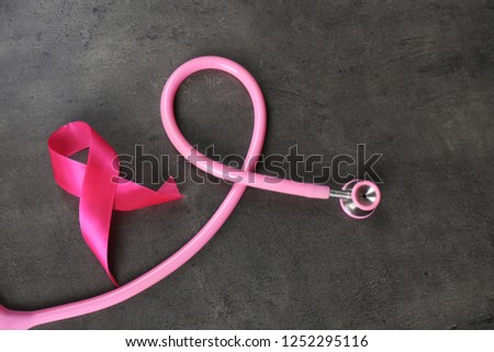 Pink ribbon with stethoscope on dark background. Breast cancer concept