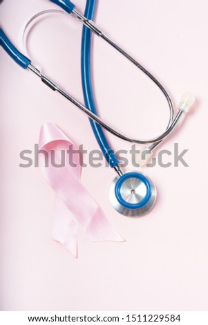 Pink ribbon, symbol of breast cancer awareness with stethoscope close up over pink background