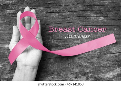 Pink ribbon symbolic bow color for Breast cancer awareness in October month (bow isolated with clipping path) on woman's hand support - Shutterstock ID 469141853