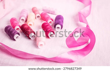 Pink ribbon and thread spools on white surface, sewing, ribbons,