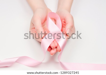 Pink ribbon in woman hands isolated on white. Breast Cancer Awareness ribbon.