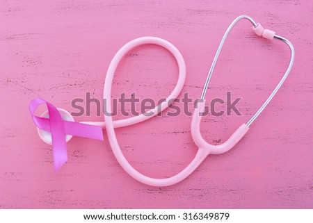 Pink Ribbon womens breast cancer awareness with stethoscope on pink wood table with ribbon symbol.