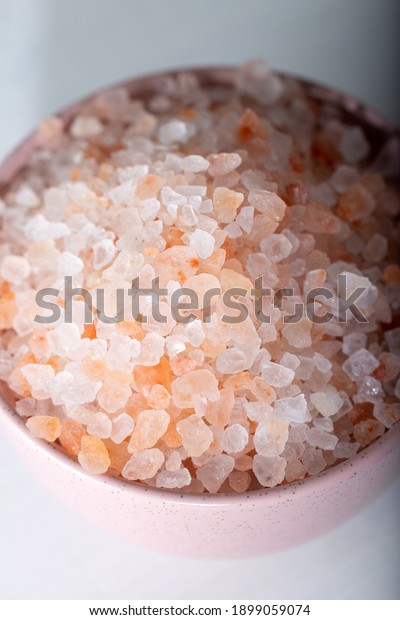 Pink rock salt in a pink bowl on a white\
background. Himalayan salt in bowl.\
